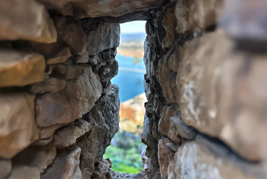 A lake seen through a weathered stone wall